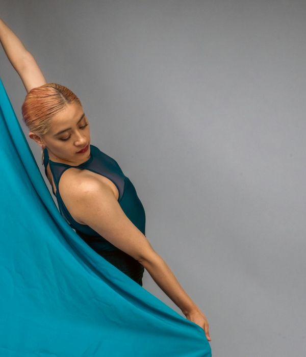 Woman performing a fluid cardio movement in a dark studio with neon blue highlights.